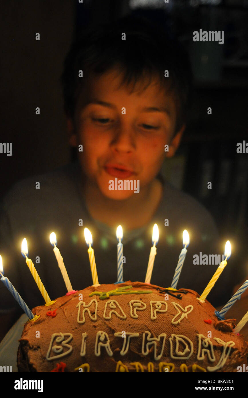 Ein zehn Jahre alter Junge bläst die Kerzen seiner Geburtstagstorte Stockfoto