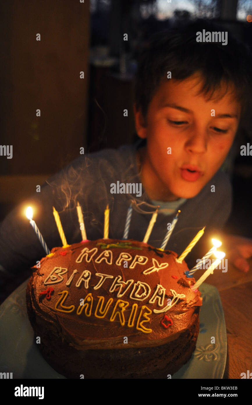 Ein zehn Jahre alter Junge bläst die Kerzen seiner Geburtstagstorte Stockfoto