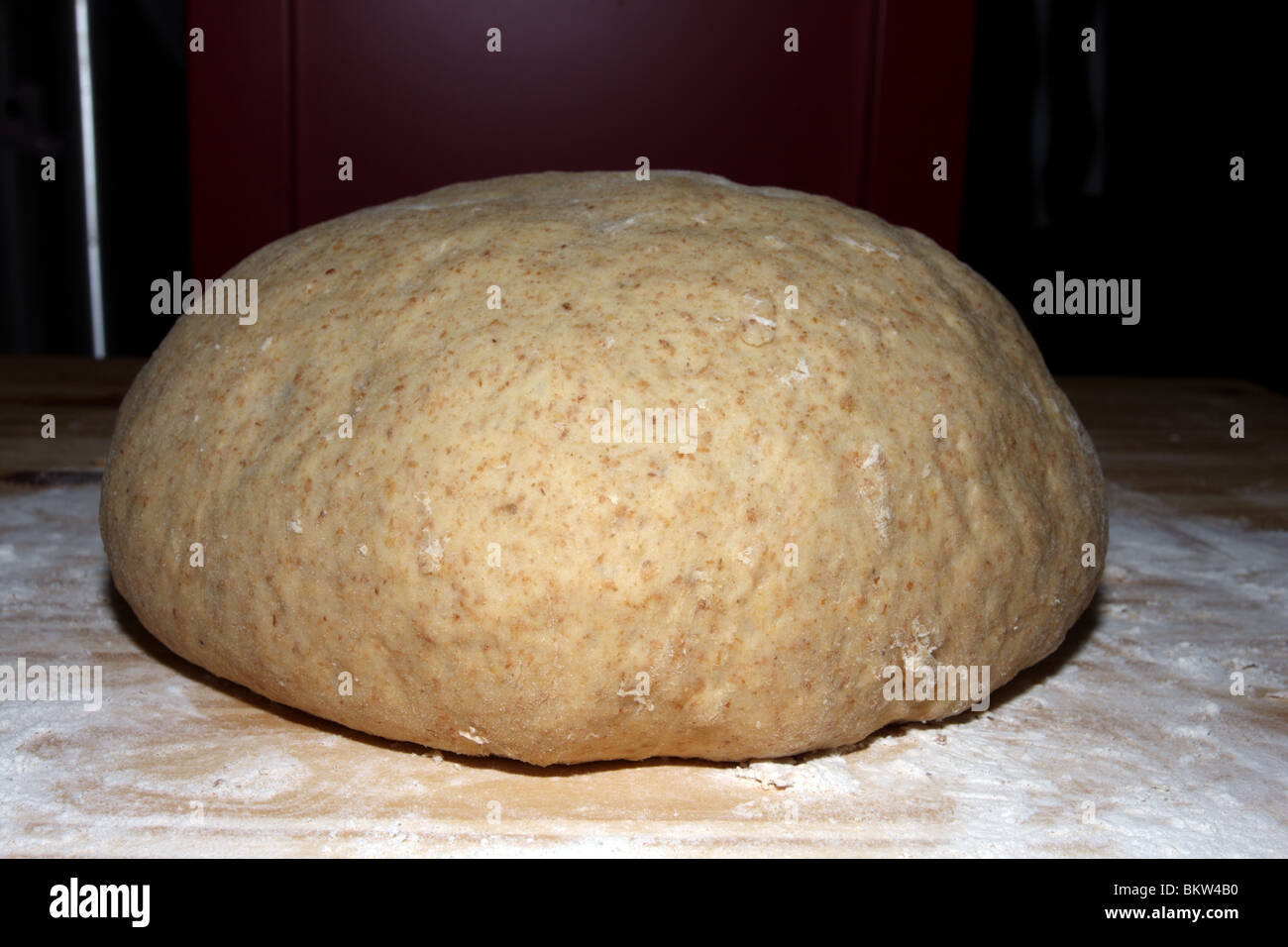 Teig-Masse steigt auf bemehlten Arbeitsfläche auf dunklem Hintergrund. Stockfoto