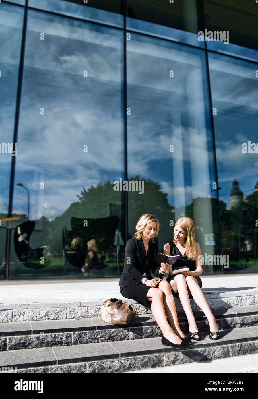 Zwei Geschäftsfrauen in Steintreppe, die Pläne zu sitzen Stockfoto