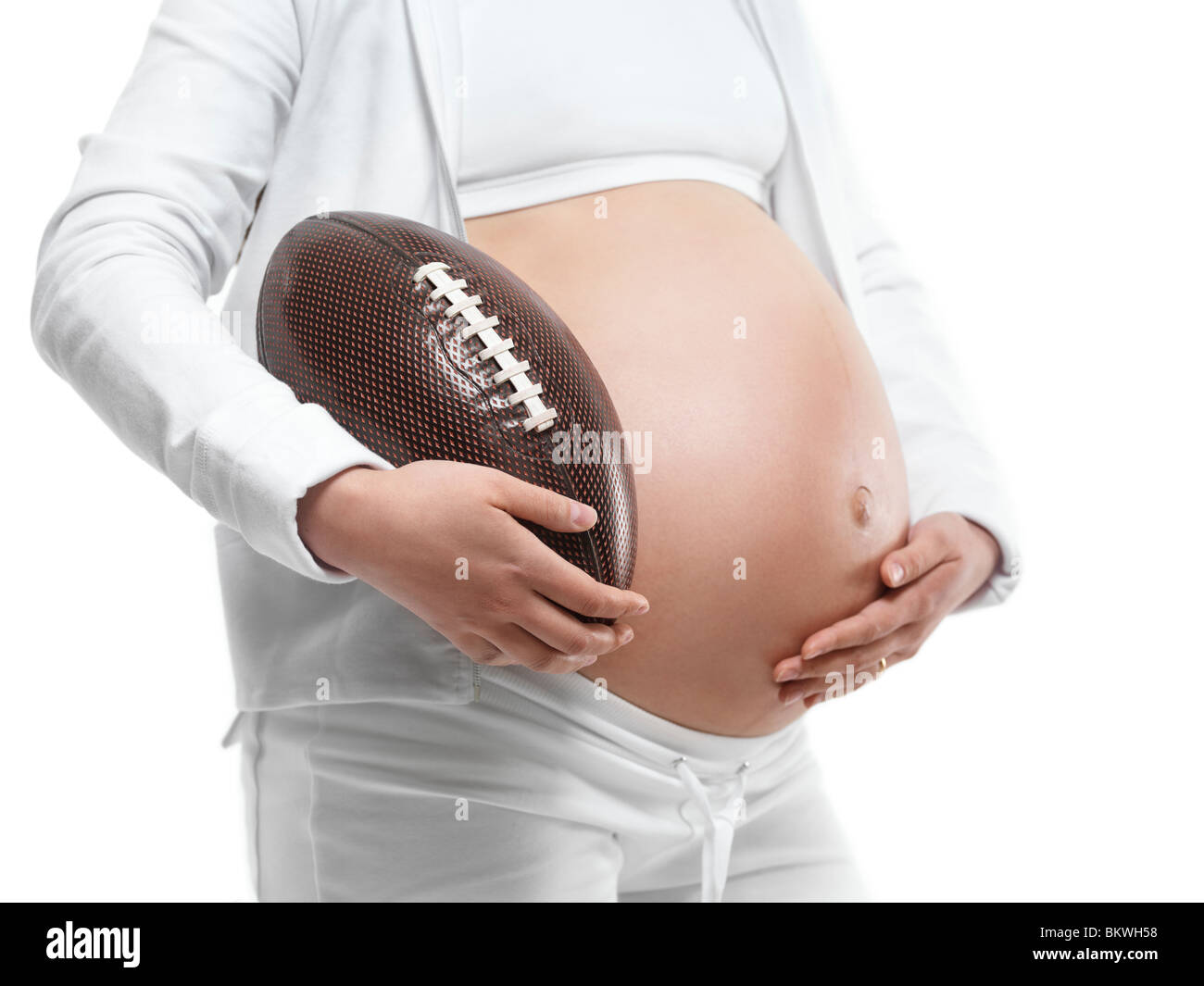 Schwangere junge Frau hält einen Fußball unter dem Arm. Isoliert auf weißem Hintergrund. Stockfoto