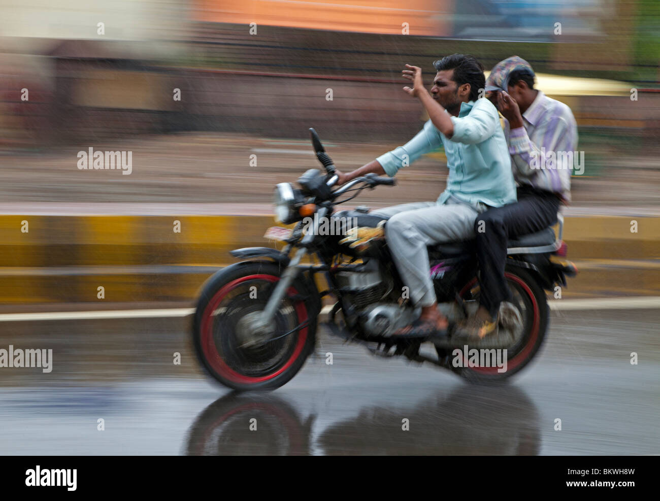 Indien, Uttar Pradesh, Agra, Motorradfahrer und Beifahrer im schweren Monsun-Regen Stockfoto
