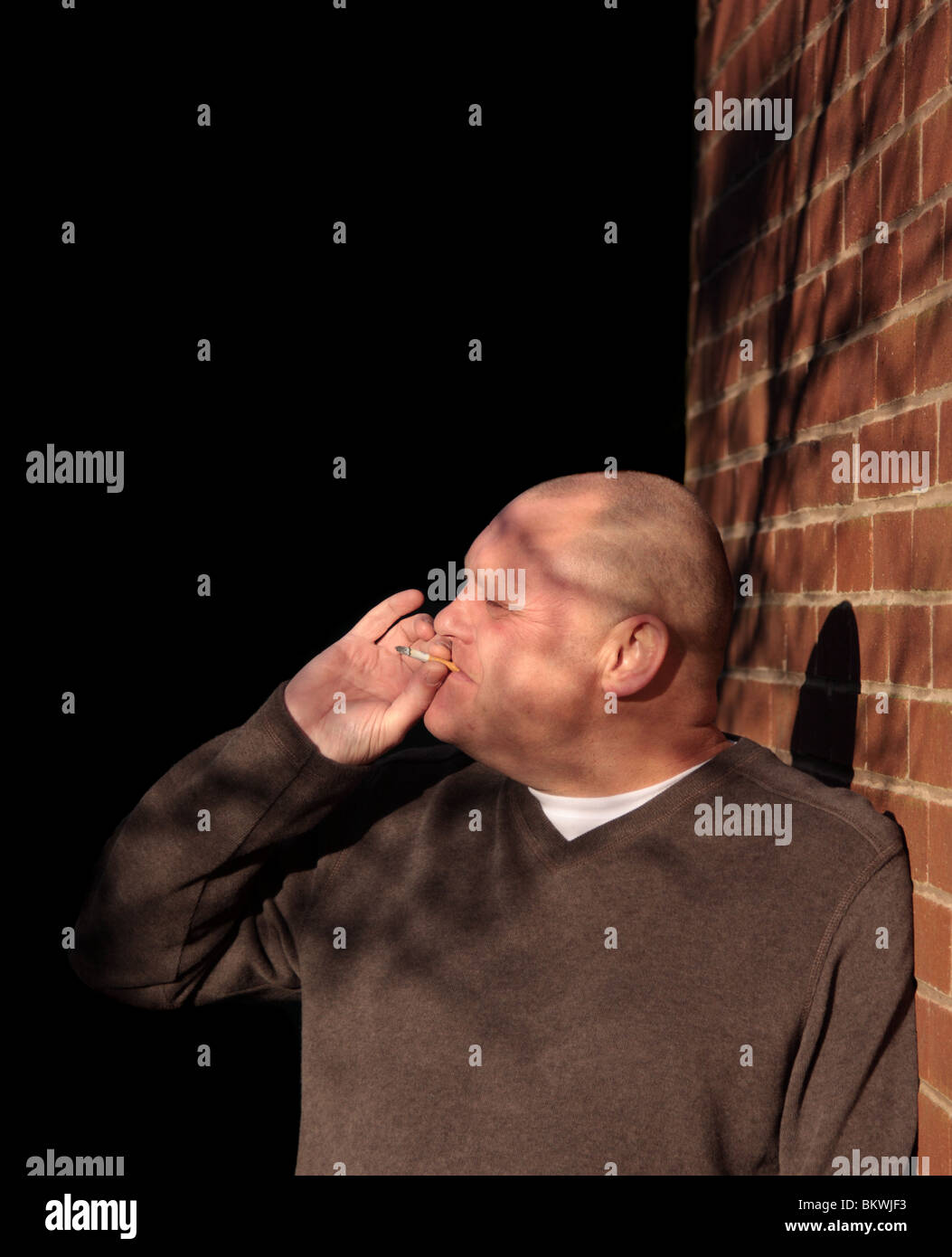Man lehnte sich gegen die Wand Rauchen Zigarette Stockfoto