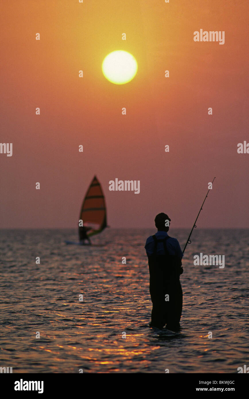 Ein Windsurfer und Surf Fischer bei Sonnenuntergang in Laguna Madre auf South Padre Island, Texas Stockfoto