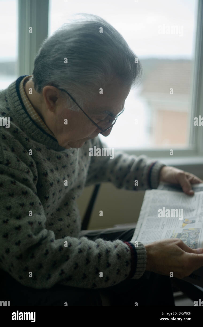 Alter Mann liest Zeitung durch Fenster Stockfoto