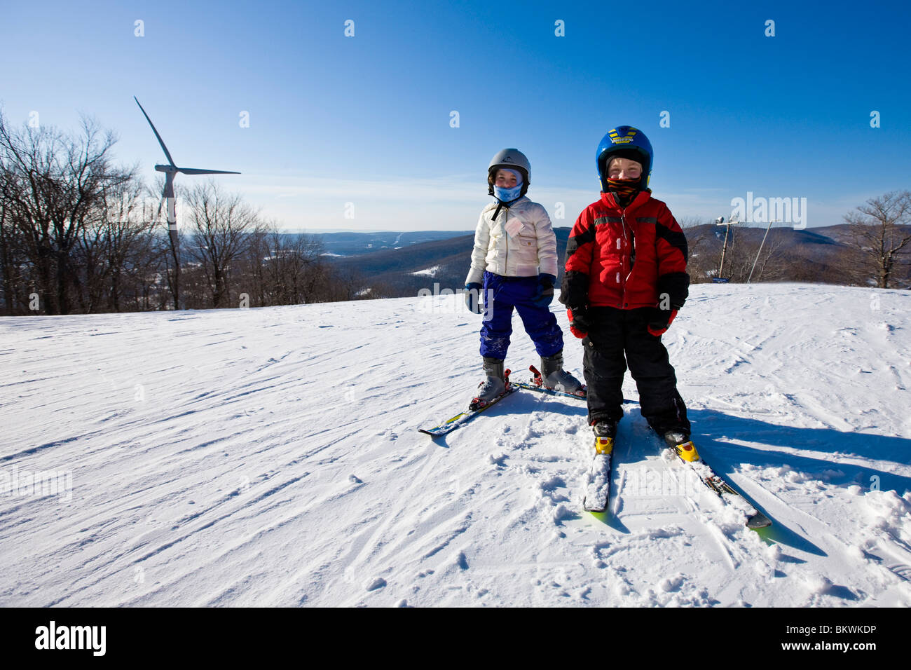 Zwei junge Skifahrer im Skigebiet Jiminy Peak in den Berkshire Mountains in Hancock, Massachusetts.  Windturbine. Stockfoto