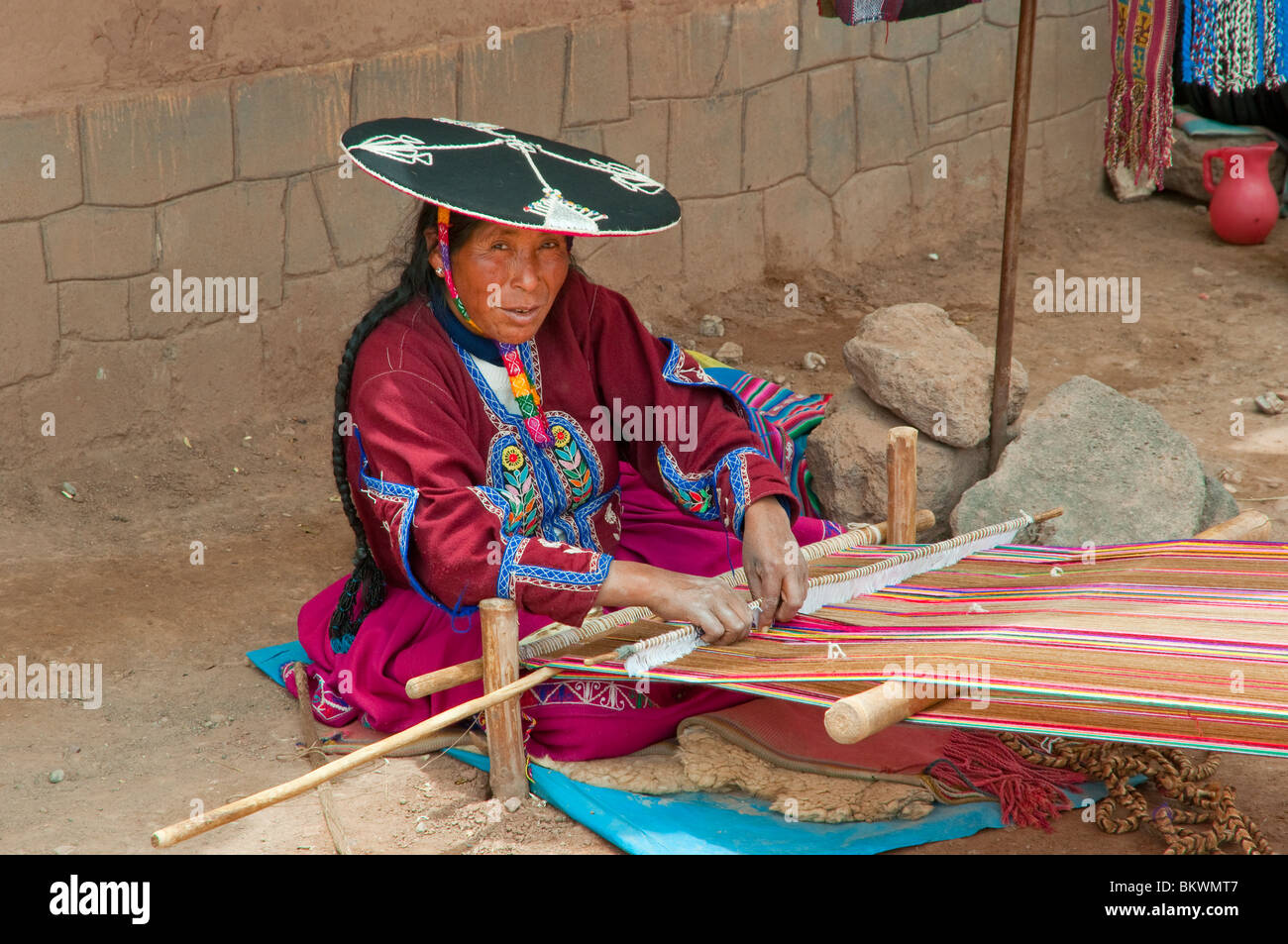 Eine peruanische Frau in traditioneller Kleidung Weben eine Decke auf dem Platz in Racchi, Peru, Südamerika. Stockfoto