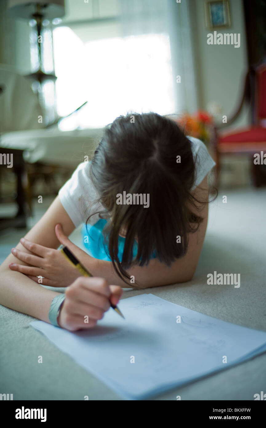 Zehn Jahre altes Mädchen mit langen Haaren macht Hausaufgaben im Wohnzimmer Stock. Stockfoto