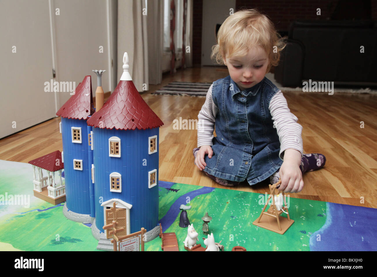 NORDISCHES KLEINKIND mit MOOMIN CASTLE: Ein zweijähriges Mädchen Kleinkind spielt mit der Spielzeugpuppe Modellhaus moomin moomins Model Stockfoto