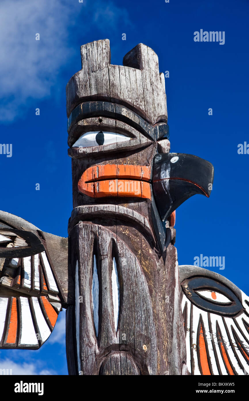 Ein geschnitzter Vogel konfrontiert Totempfahl. Stockfoto