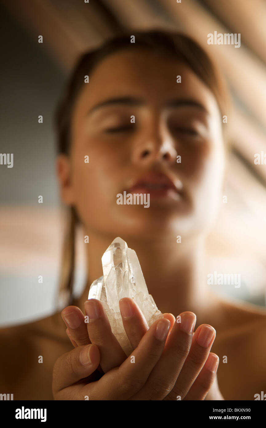 Junge Frau, die Kristall in ihren Händen hält Stockfoto
