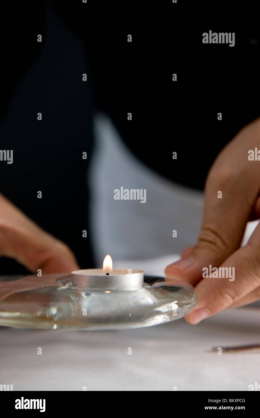 Nahaufnahme von einem Kellner Hände Positionierung ein Teelicht auf einem Tisch im restaurant Stockfoto