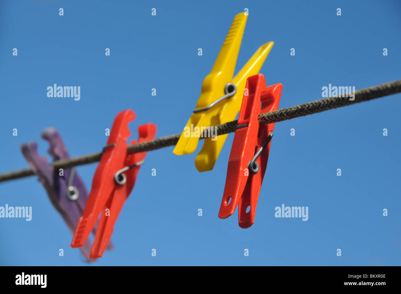 rote, gelbe und blaue Wäscheklammern an einer Wäscheleine. Stockfoto