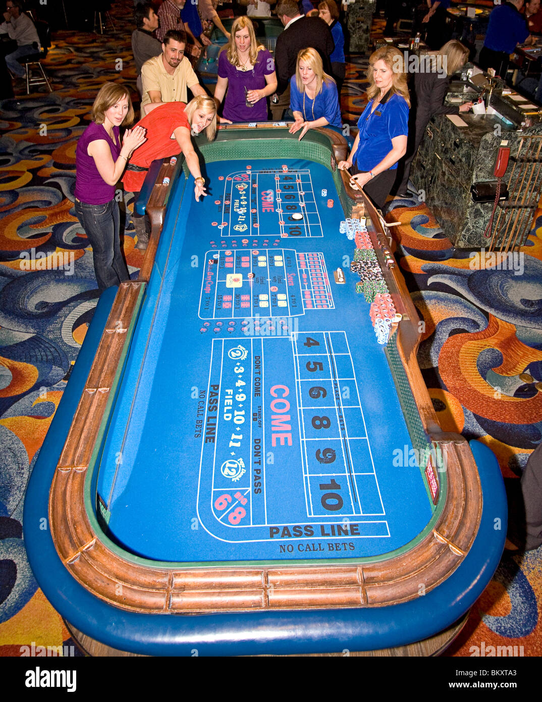 Szene auf Gaming-Etage des Casino - erregte Frau wirft Würfel am Craps-Tisch, während ihr Freunde anzufeuern. South Lake Tahoe Stockfoto