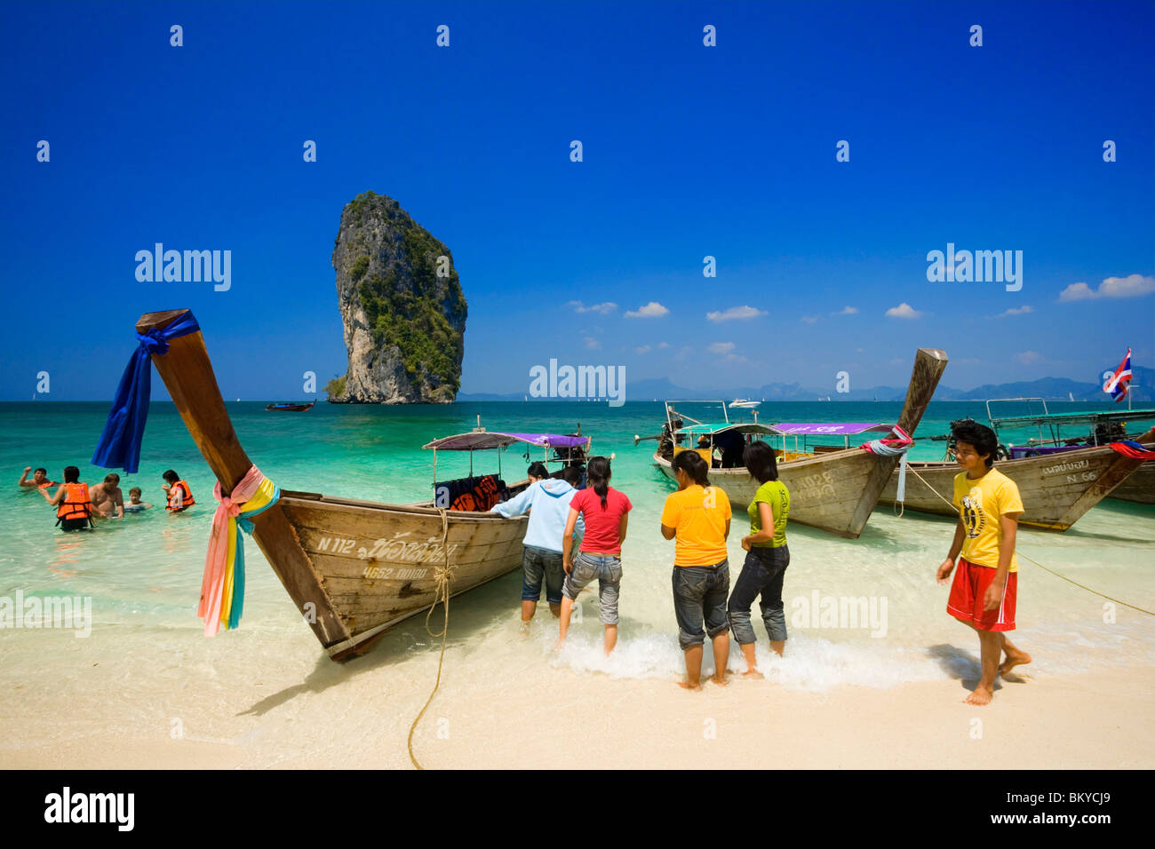 Boote verankert am Strand, Touristen mit Schwimmwesten stehen im Wasser, Ko Poda im Hintergrund, Laem Phra Nang, Railay, Krabi, Thailändisch Stockfoto