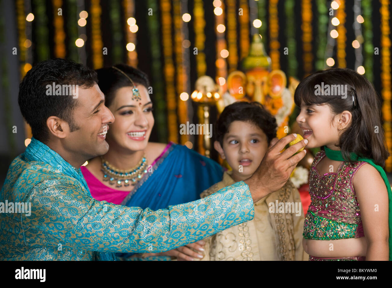 Mann, die Verfütterung von Süßigkeiten an seine Kinder auf Diwali Stockfoto