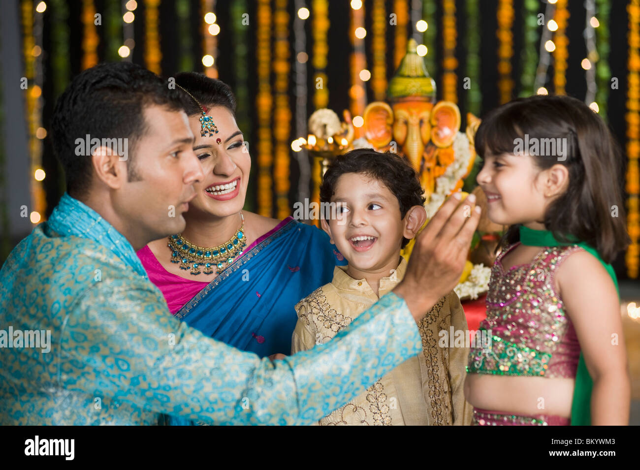 Mann, die Verfütterung von Süßigkeiten an seine Kinder auf Diwali Stockfoto