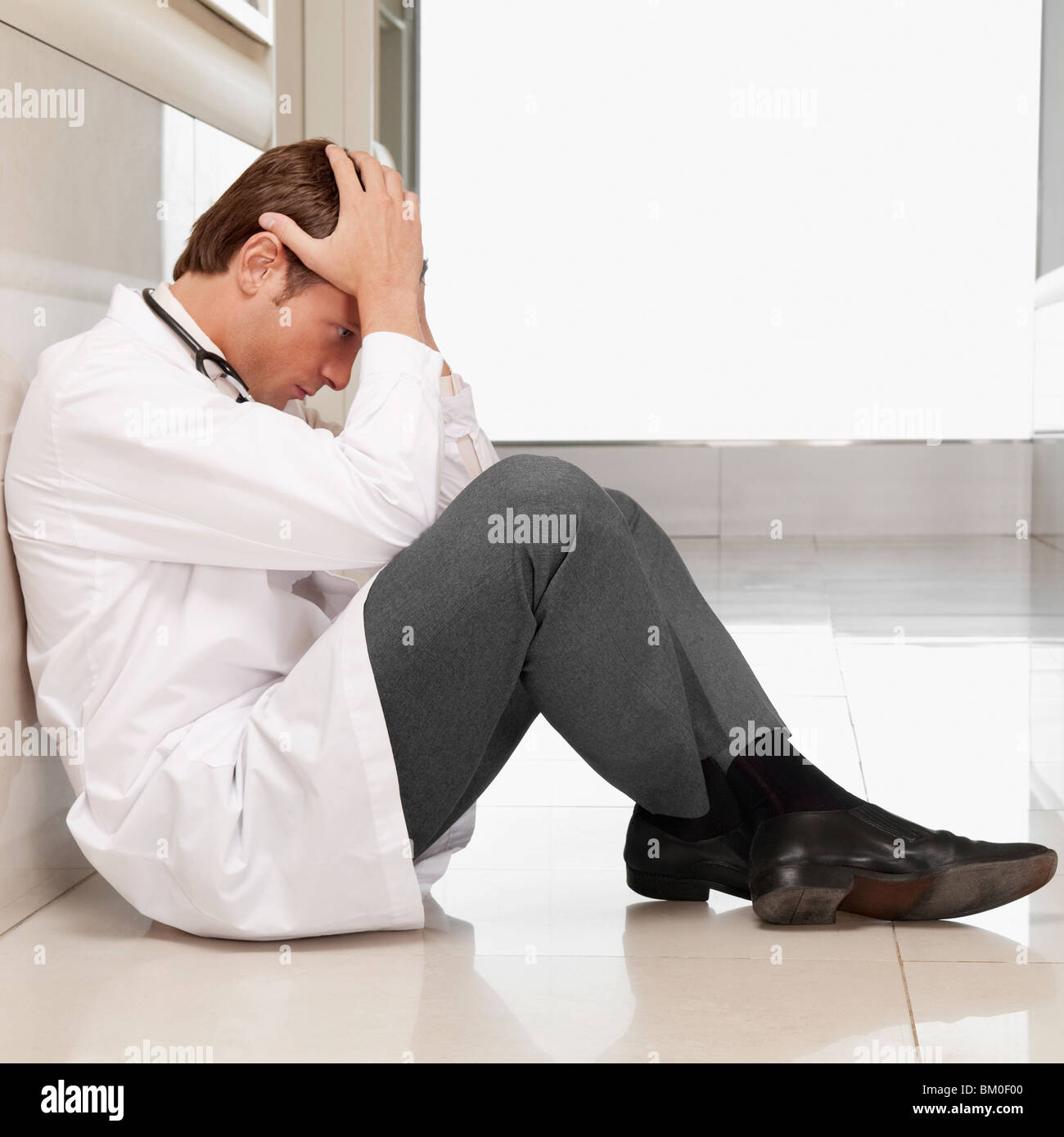 Arzt, sitzen auf dem Boden auf der Suche deprimiert Stockfoto