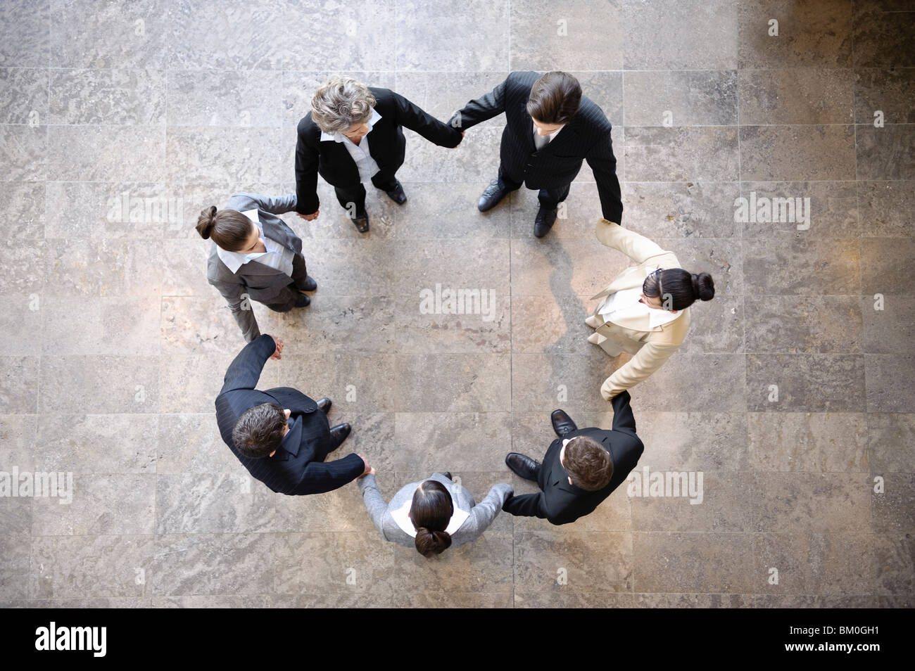 Geschäftsleute, die Hand in Hand im Kreis Stockfoto
