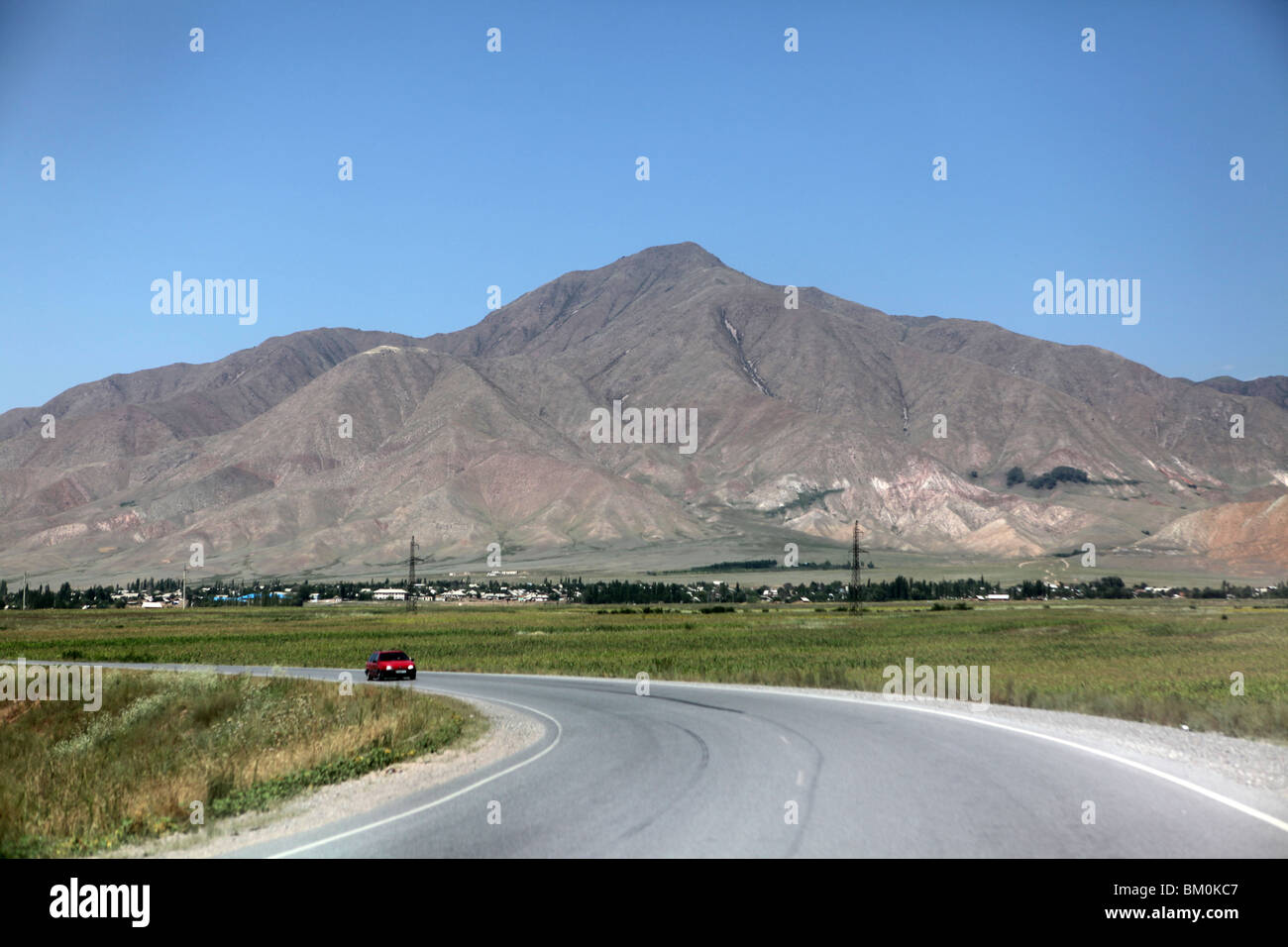 Eine asphaltierte Straße fegt vorbei an Bergen in Kirgisien, Zentralasien. Stockfoto