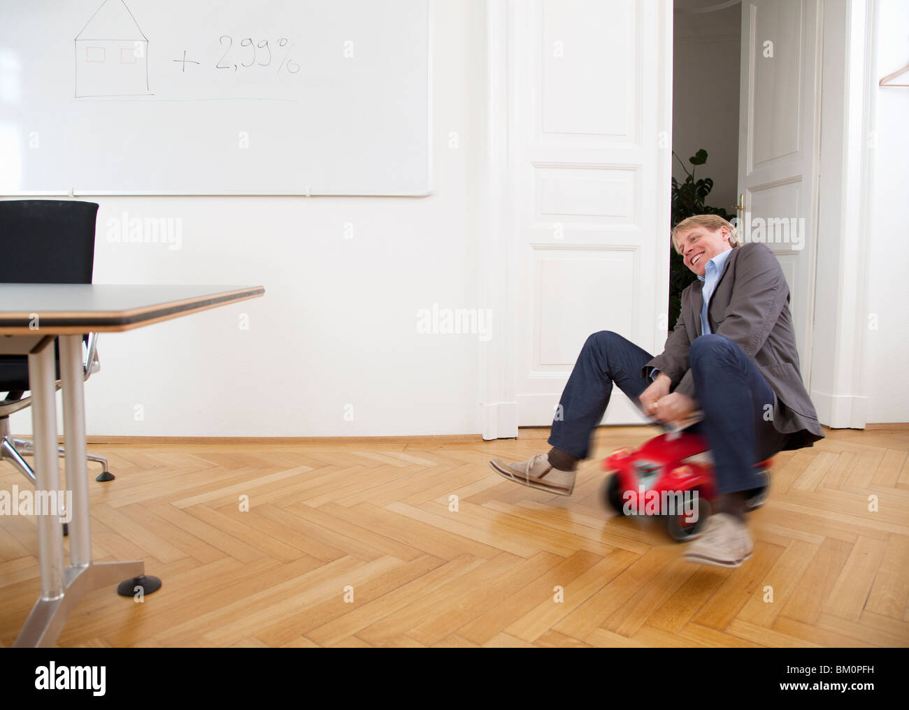 Geschäftsmann Reiten Spielzeugauto im Büro Stockfoto