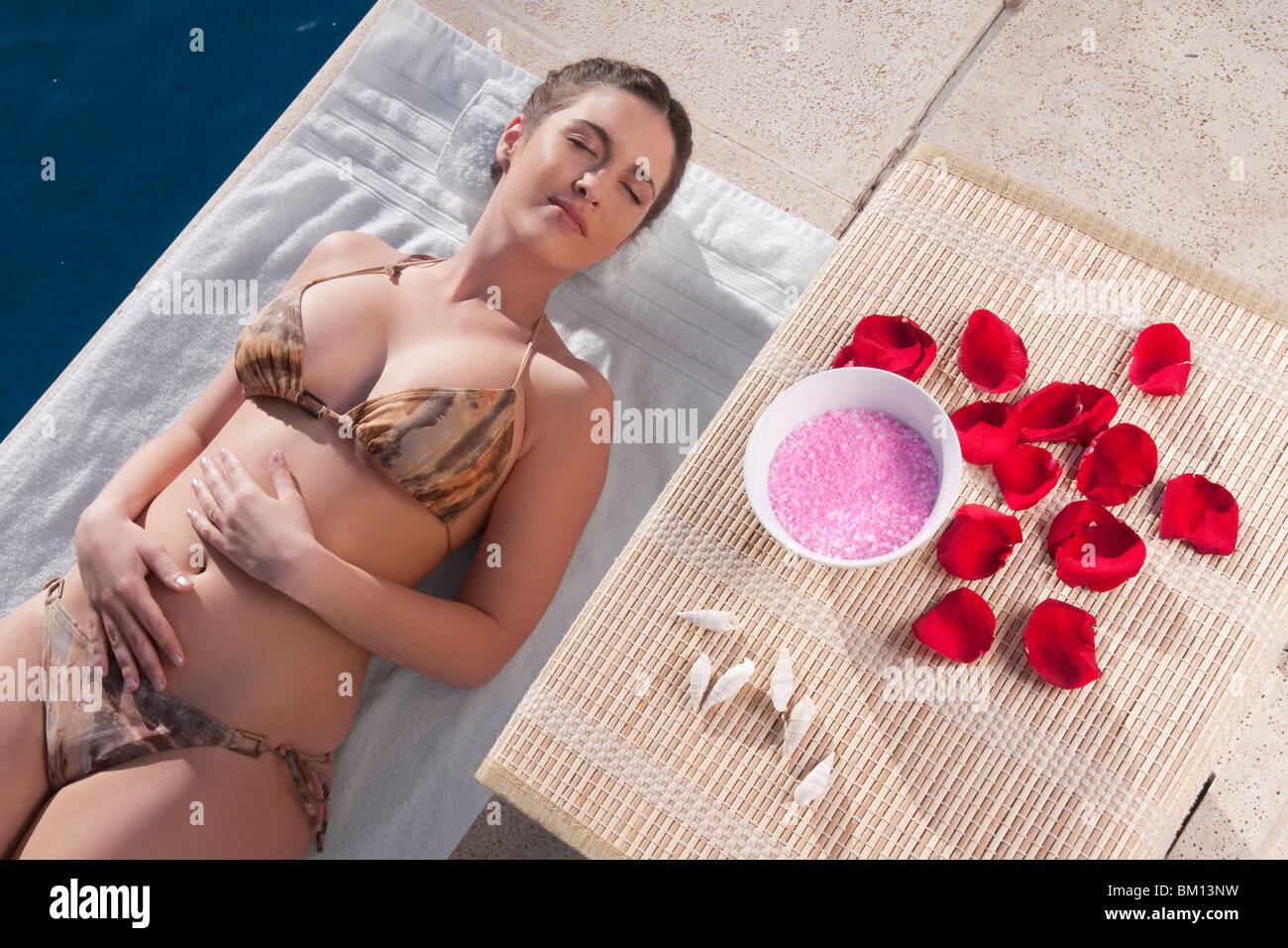 Frau mit Aroma-Produkte neben ihr am Pool ausruhen Stockfoto