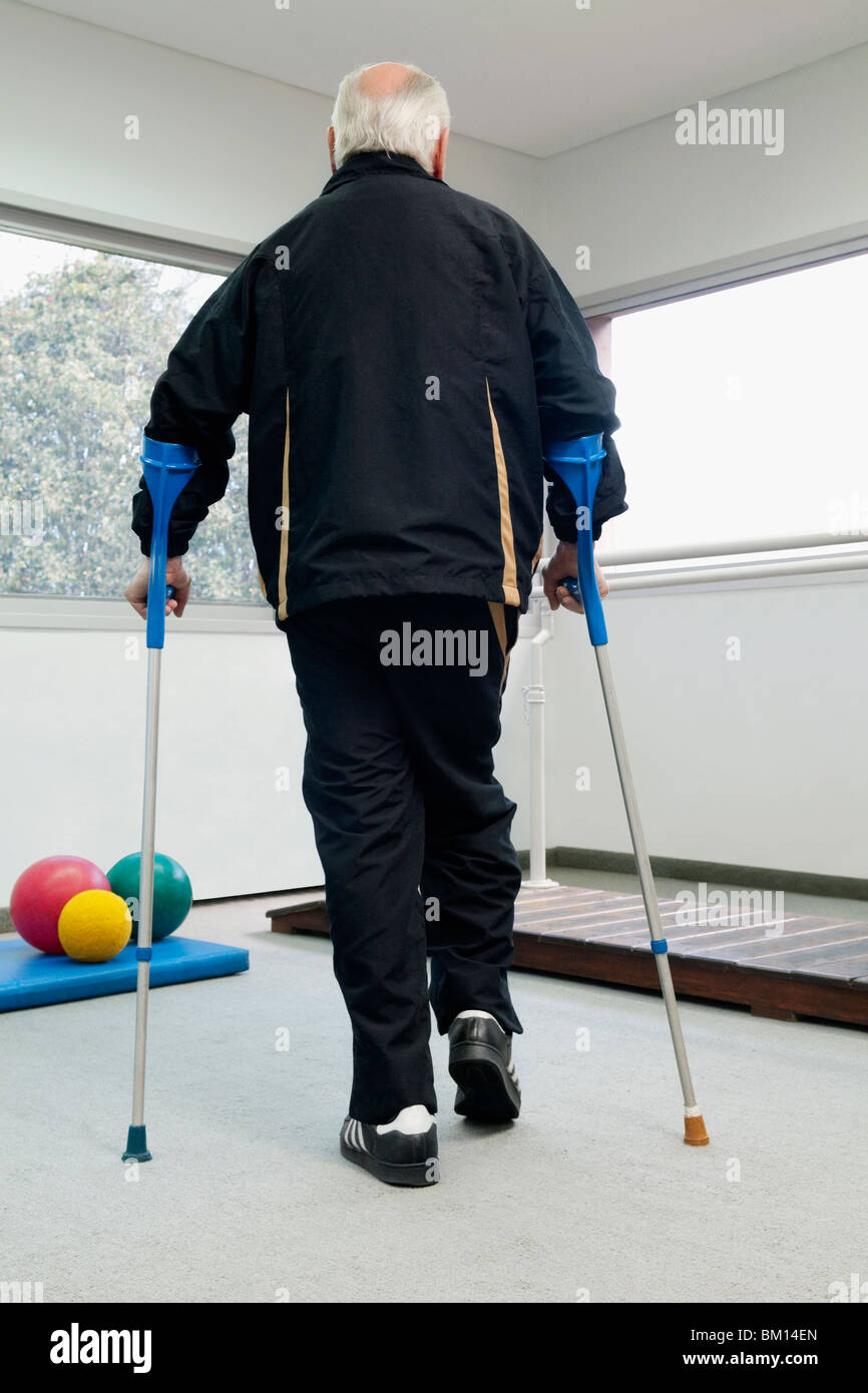 Rückansicht eines behinderten Menschen zu Fuß mit Hilfe von Krücken Stockfoto