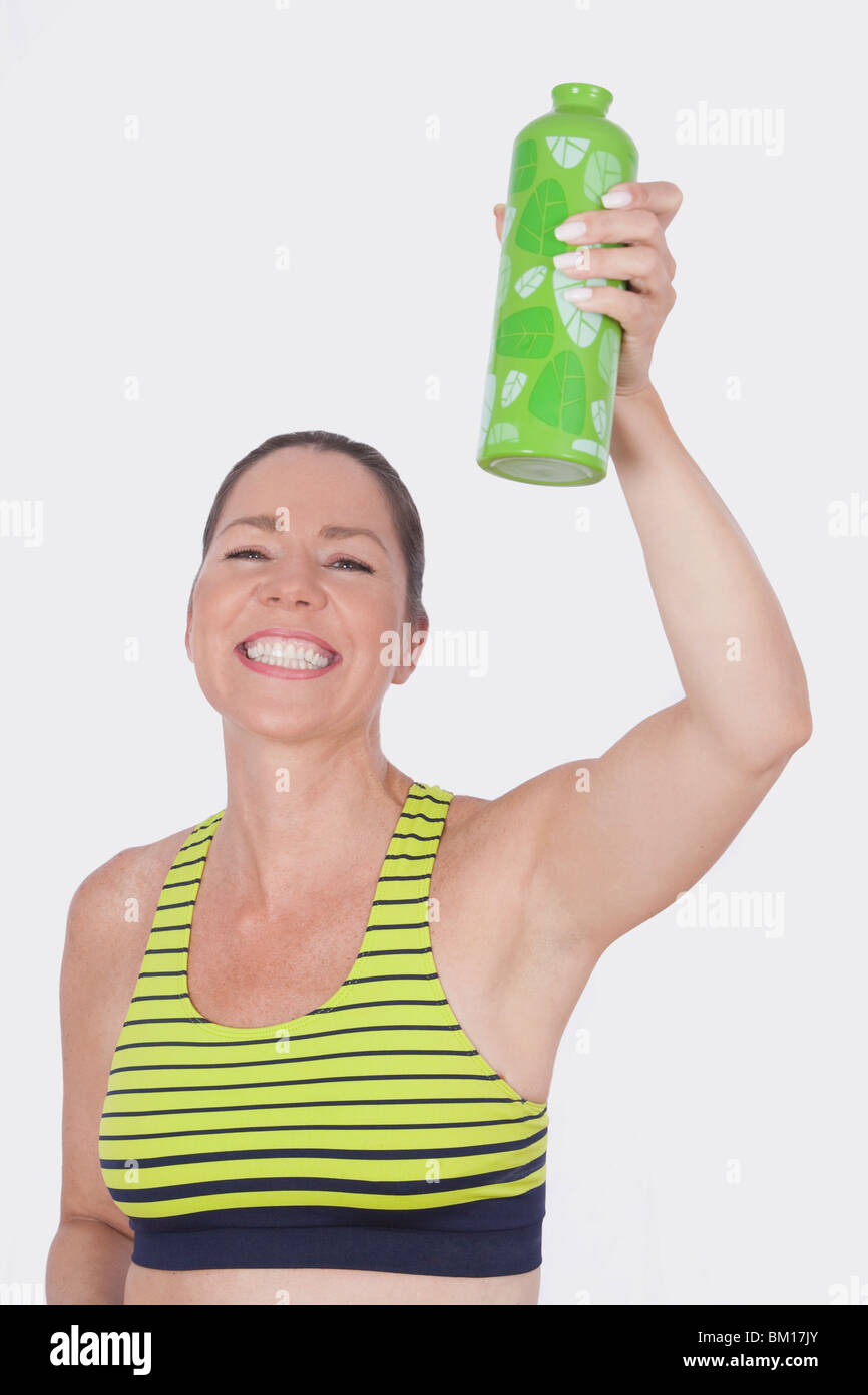 Porträt einer Frau hält eine Flasche Wasser und lächelnd Stockfoto
