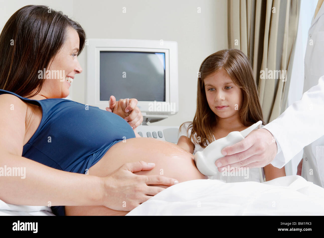 Schwangere Frau wird durch eine Ultraschalluntersuchung mit ihrer Tochter sah Sie Stockfoto