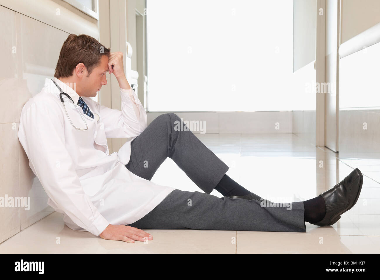 Arzt, sitzen auf dem Boden auf der Suche deprimiert Stockfoto
