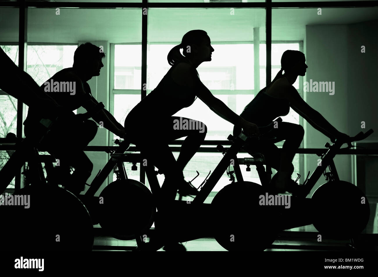 Silhouette von vier Personen arbeiten auf Ergometern in ein Fitness-Studio Stockfoto