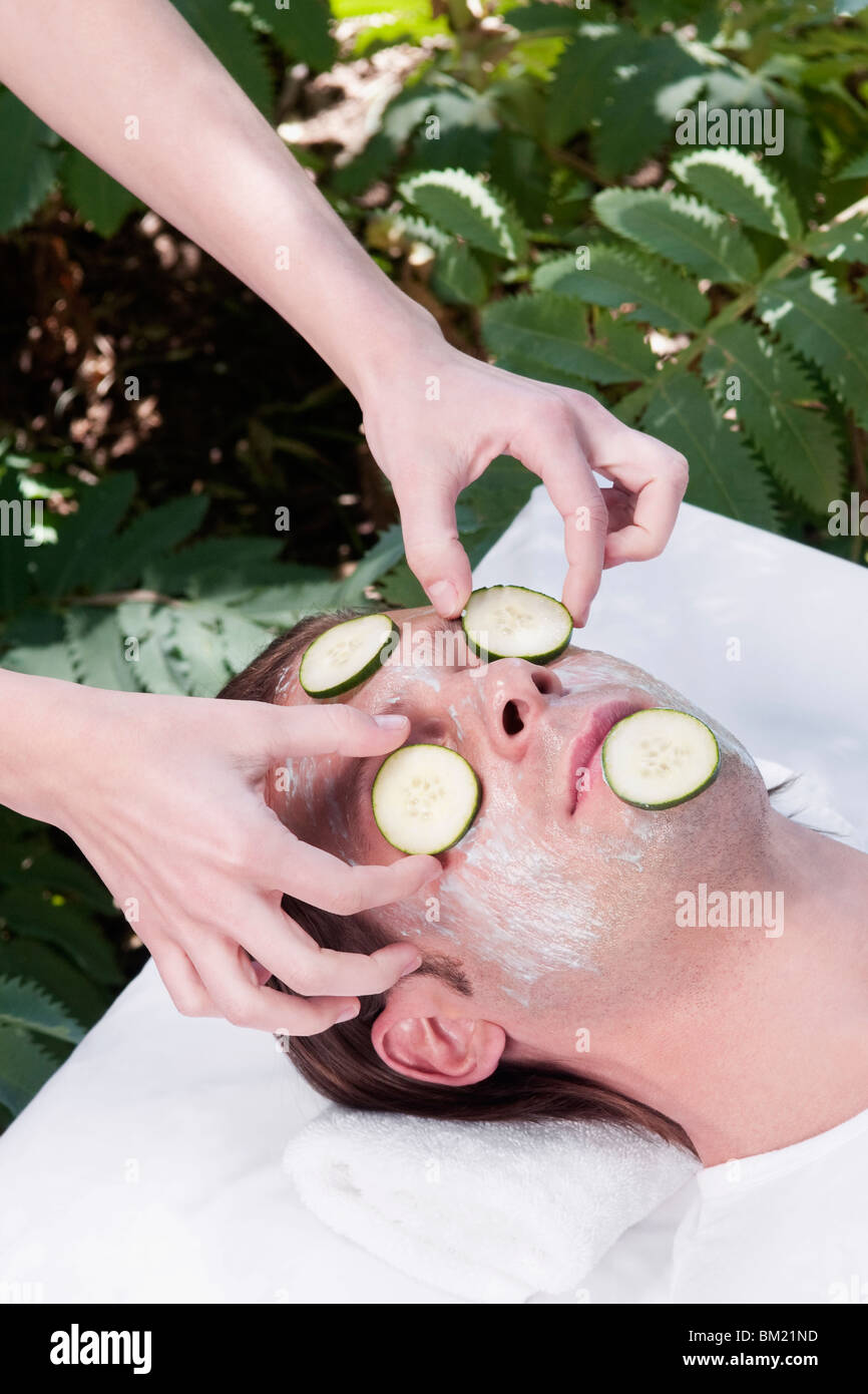 Kosmetikerin, Gurkenscheiben auf das Gesicht des Mannes Stockfoto
