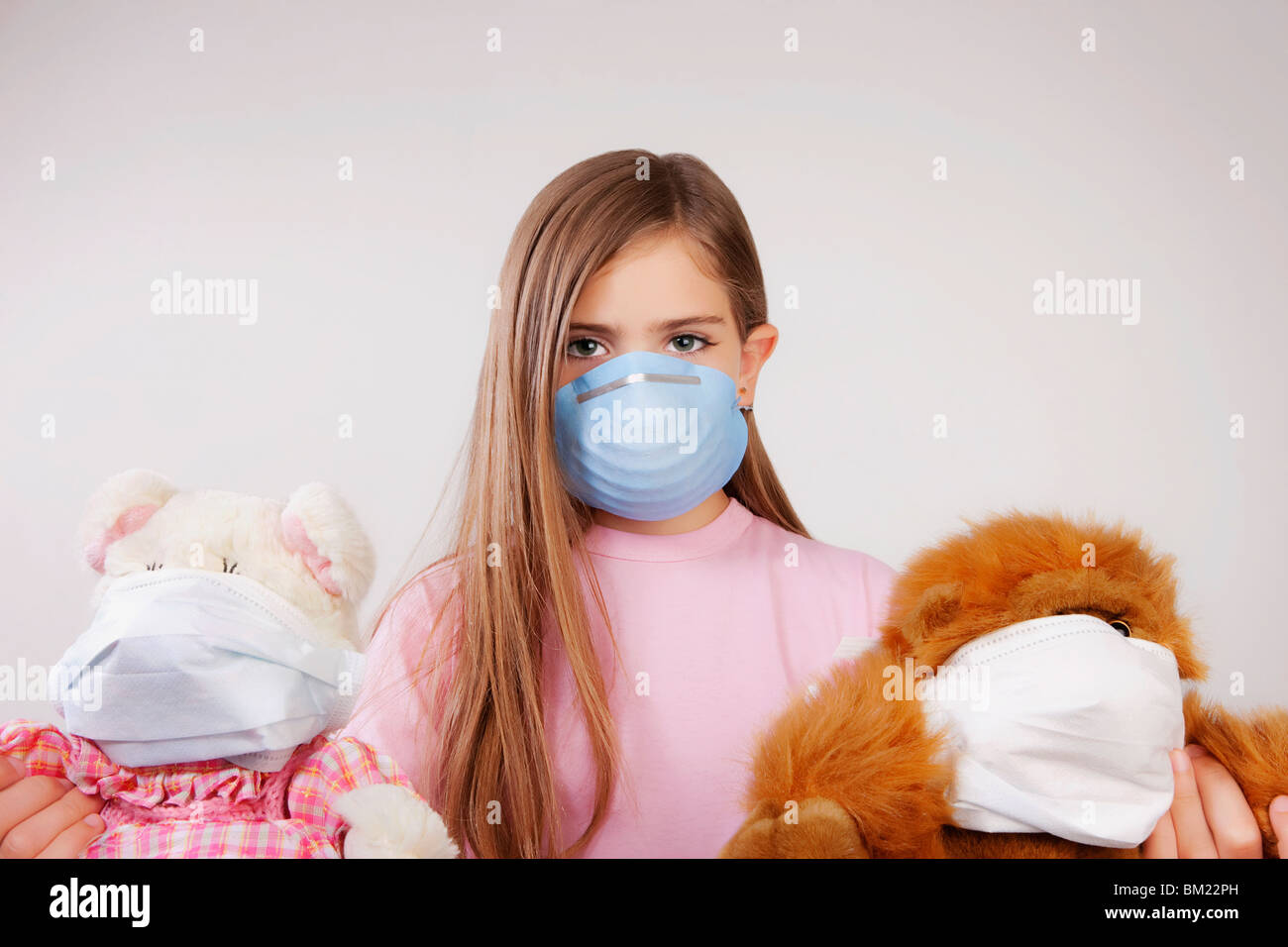Porträt eines Mädchens eine Grippe-Maske trägt und hält die Stoffspielzeuge Stockfoto