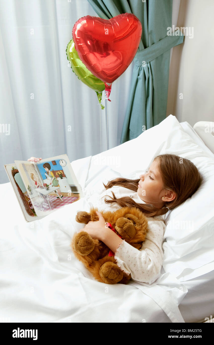 Mädchen, ein Comic-Buch in einem Krankenhausbett Stockfoto