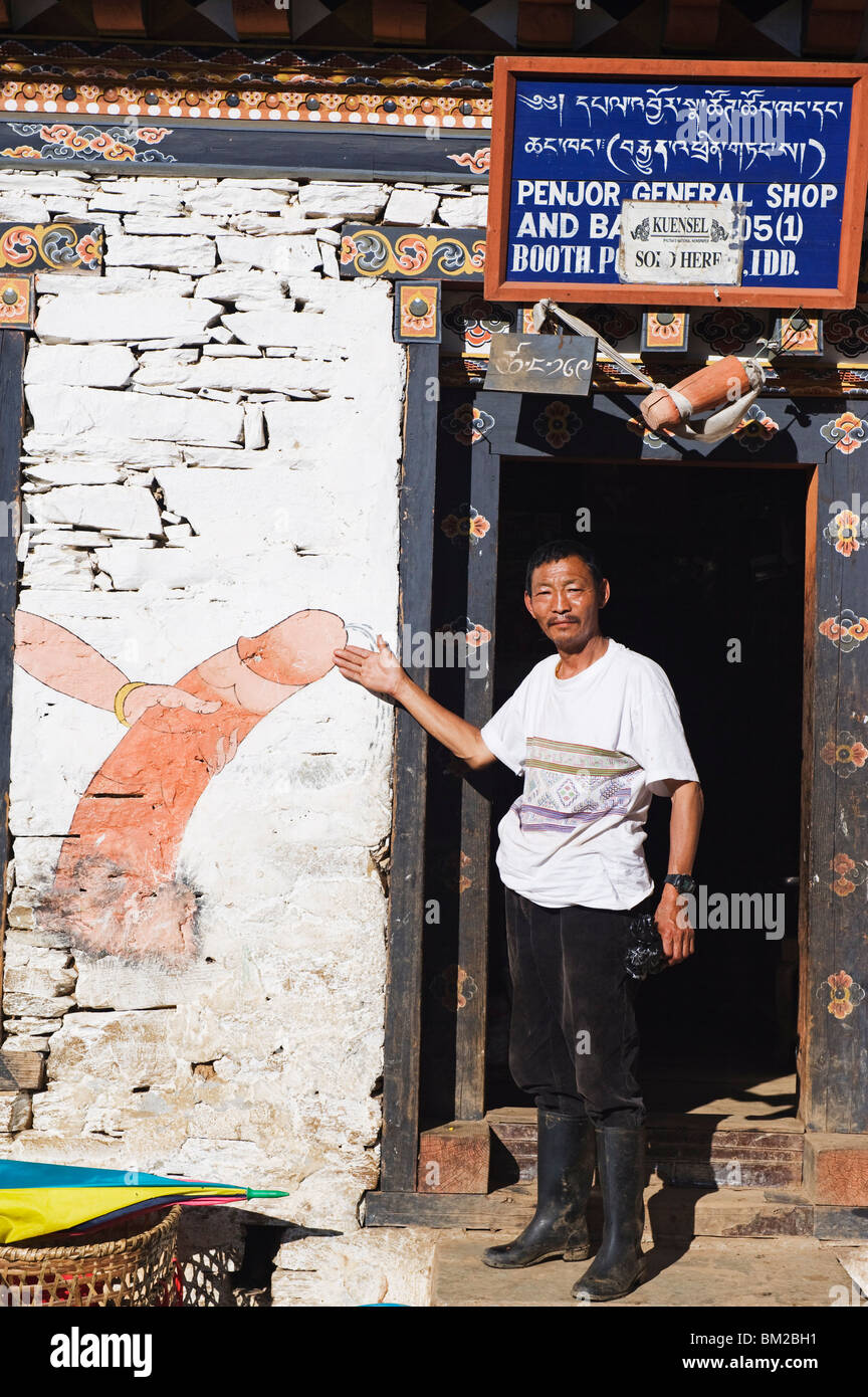 Mann zeigt eine phallische Malerei auf einer Shop-Wand, Bhutan Stockfoto