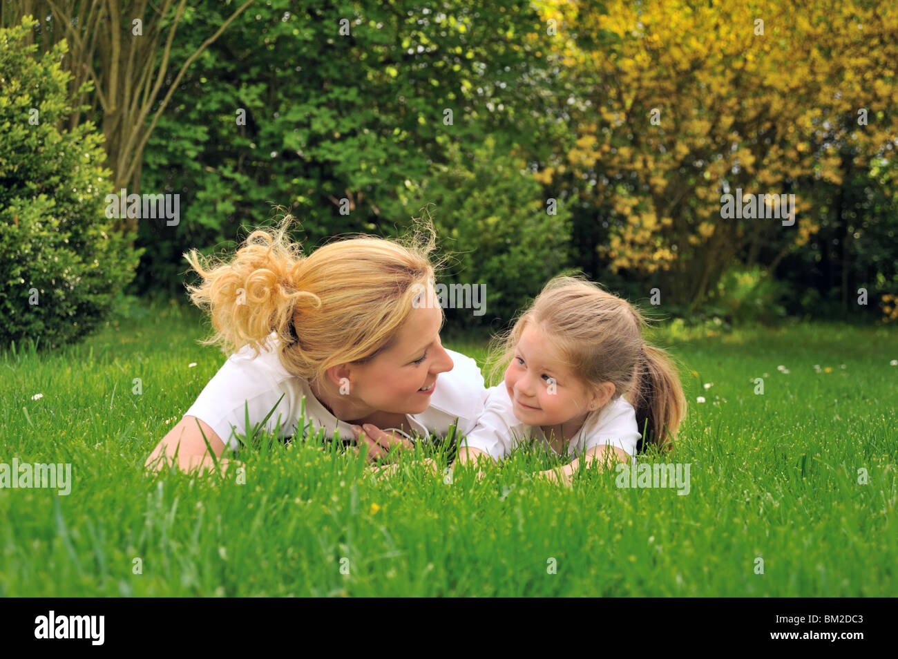 Junge Mutter und Tochter, die Verlegung auf dem Rasen Stockfoto