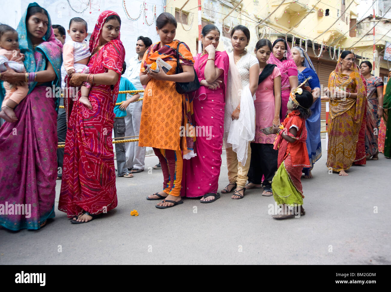 Frauen-Warteschlangen für Diwali Tempel Puja, angesprochen von einem Kind betteln um Almosen, Udaipur, Rajasthan, Indien Stockfoto
