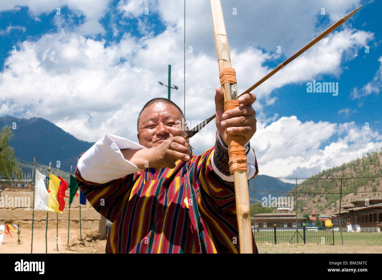 Traditionell gekleidete bhutanischen Mann üben des nationalen Sports des Bogenschießens im Nationalstadion, Thimpu, Bhutan Stockfoto