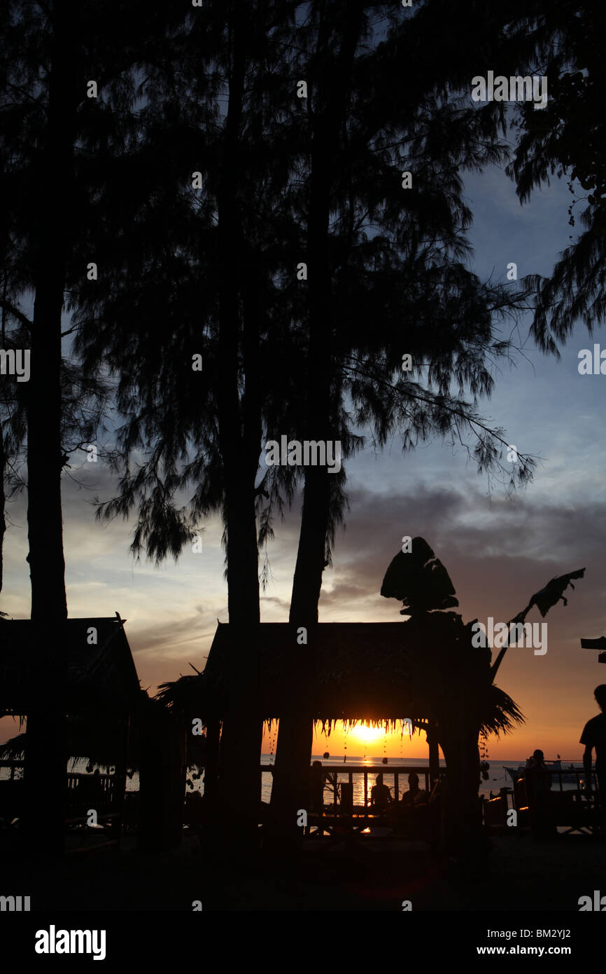 Die Sonne geht durch den Strandhütten auf Long Beach, Ko Lanta in Thailand. Stockfoto
