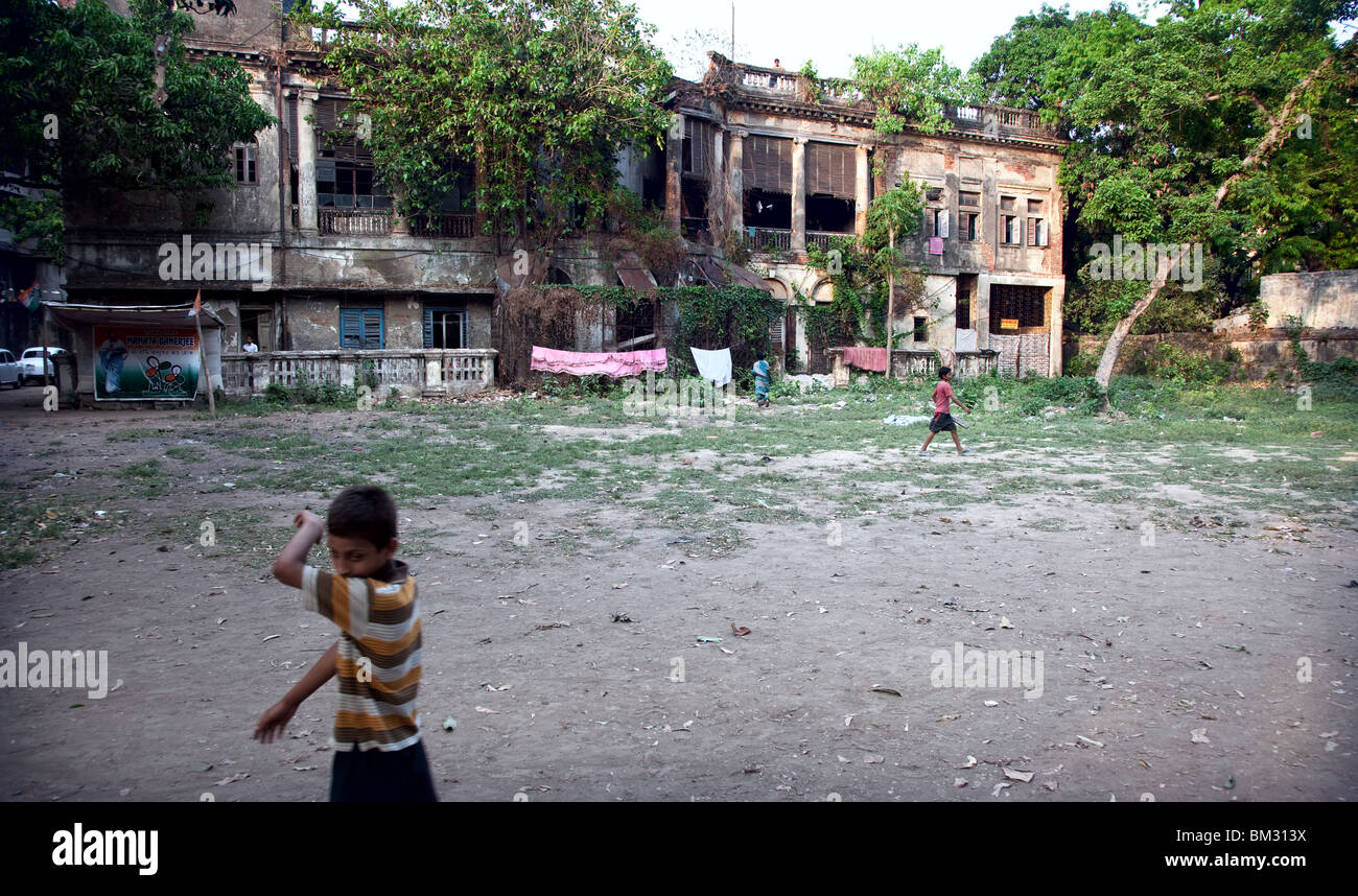 Straßenkinder spielen vor einem verfallenen Britisches Raj Ära Herrenhaus in Kolkata, Indien Straßenszenen. Stockfoto