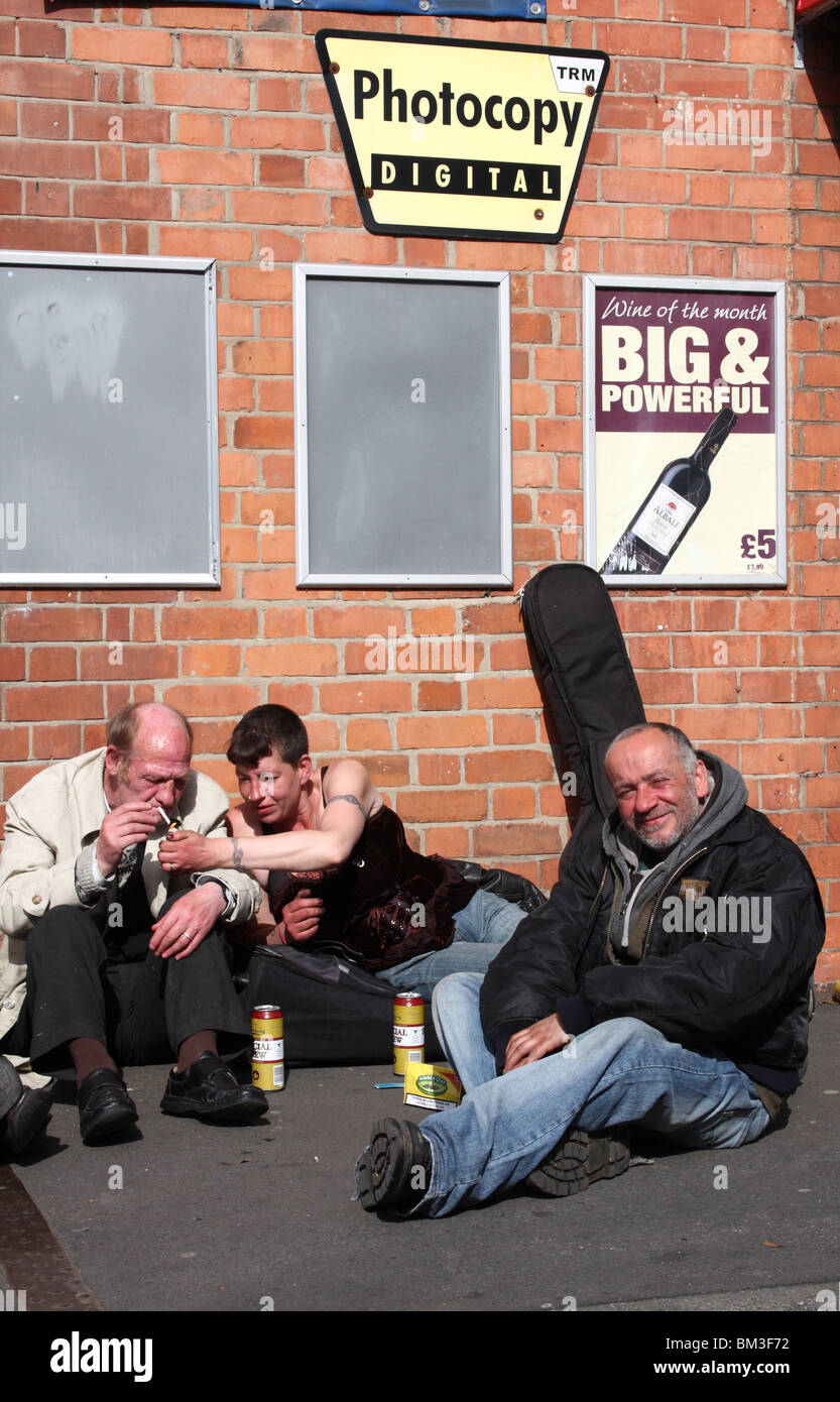 Obdachlose Menschen trinken Alkohol unter Plakate billigen Alkohol in einer Stadt, U.K. Stockfoto