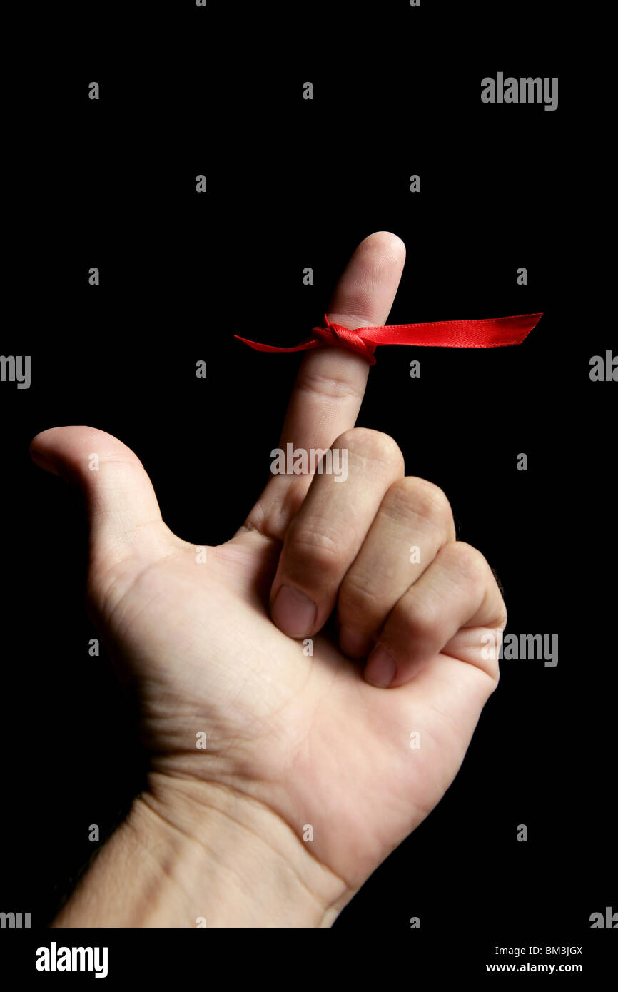 Red Tape Band, Schleife Band um menschliche Finger auf schwarzem Hintergrund Stockfoto