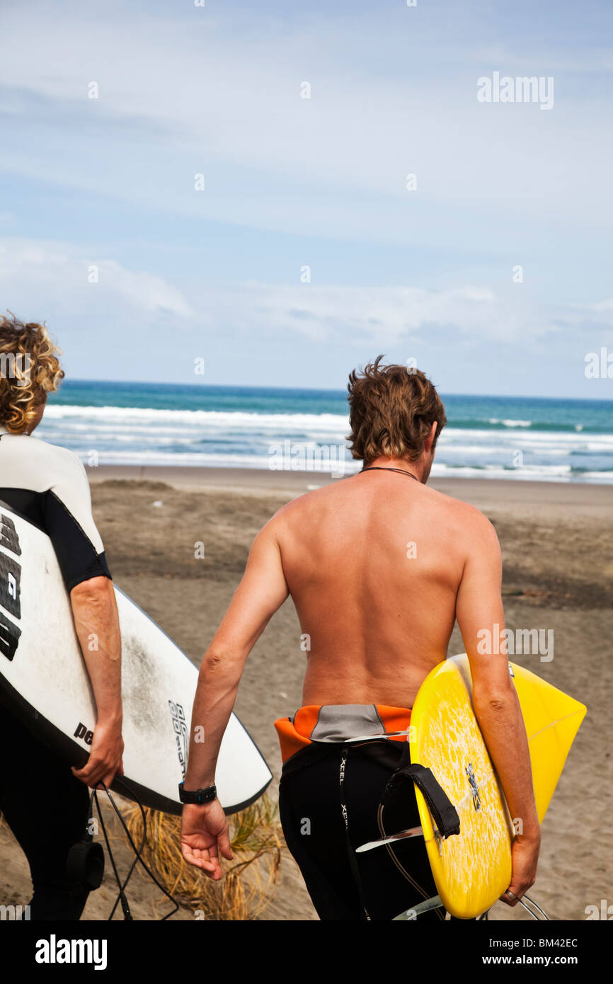 Surfer Fuß hinunter zum Strand Piha. Piha, Waitakere Ranges Regional Park, Auckland, Nordinsel, Neuseeland Stockfoto