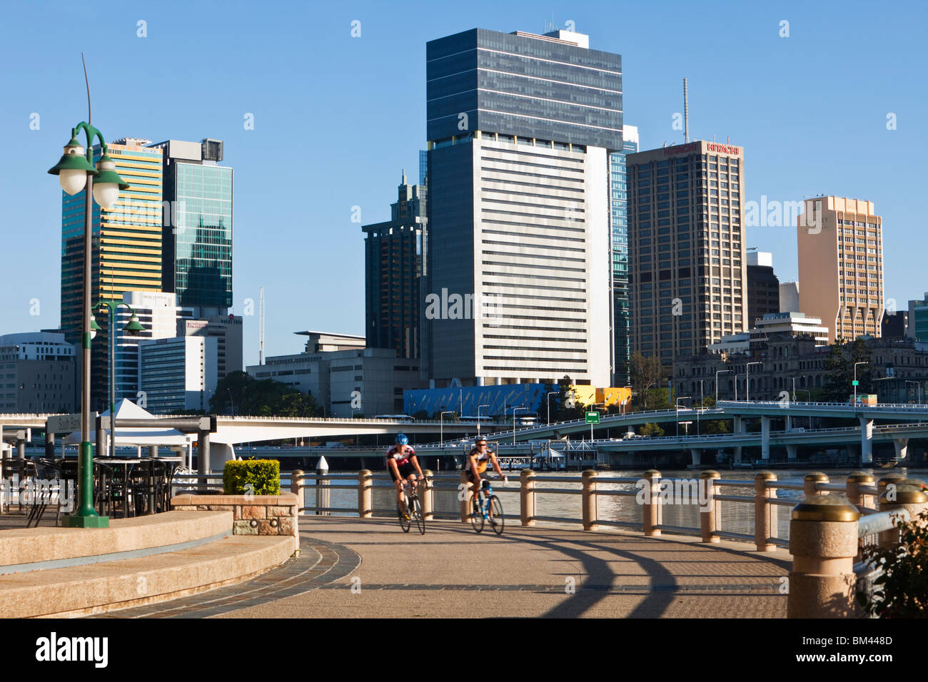 Radfahrer am Flussufer in South Bank mit Skyline der Stadt im Hintergrund. South Bank, Brisbane, Queensland, Australien Stockfoto