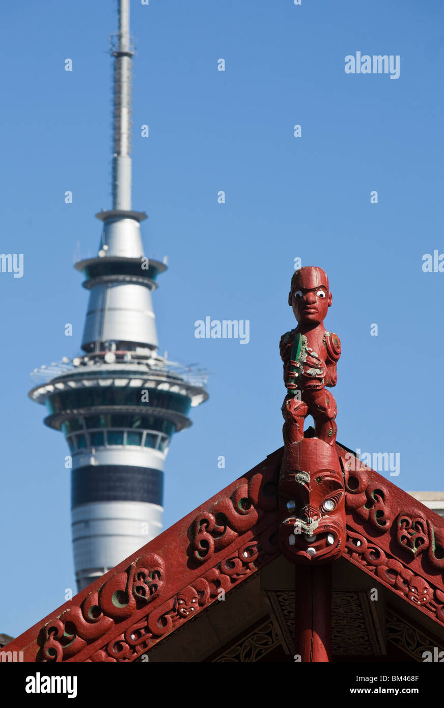 Die Maori-Schnitzereien eine Whare Runanga (Gemeindehaus) und der Sky Tower darüber hinaus. Auckland, Nordinsel, Neuseeland Stockfoto