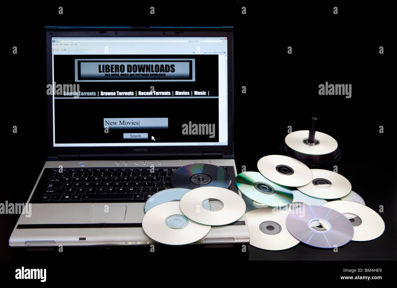 Illegale Download Website und Bittorrent-Website auf einem Computer neben einem Haufen von kopierten DVDs. Stockfoto