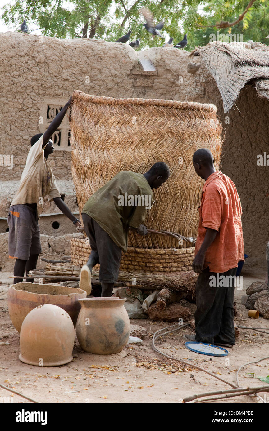 Eine Gruppe Männer bauen ein Grainery aus geflochtenen Matten aus Stroh in Kalabougou, Mali. Stockfoto