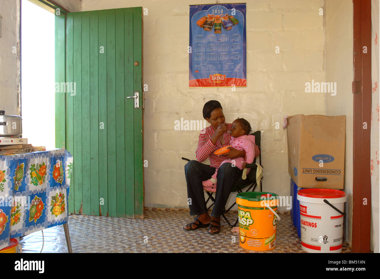 Eine Mutter füttert ihr Kind in einer Baracke. Stockfoto