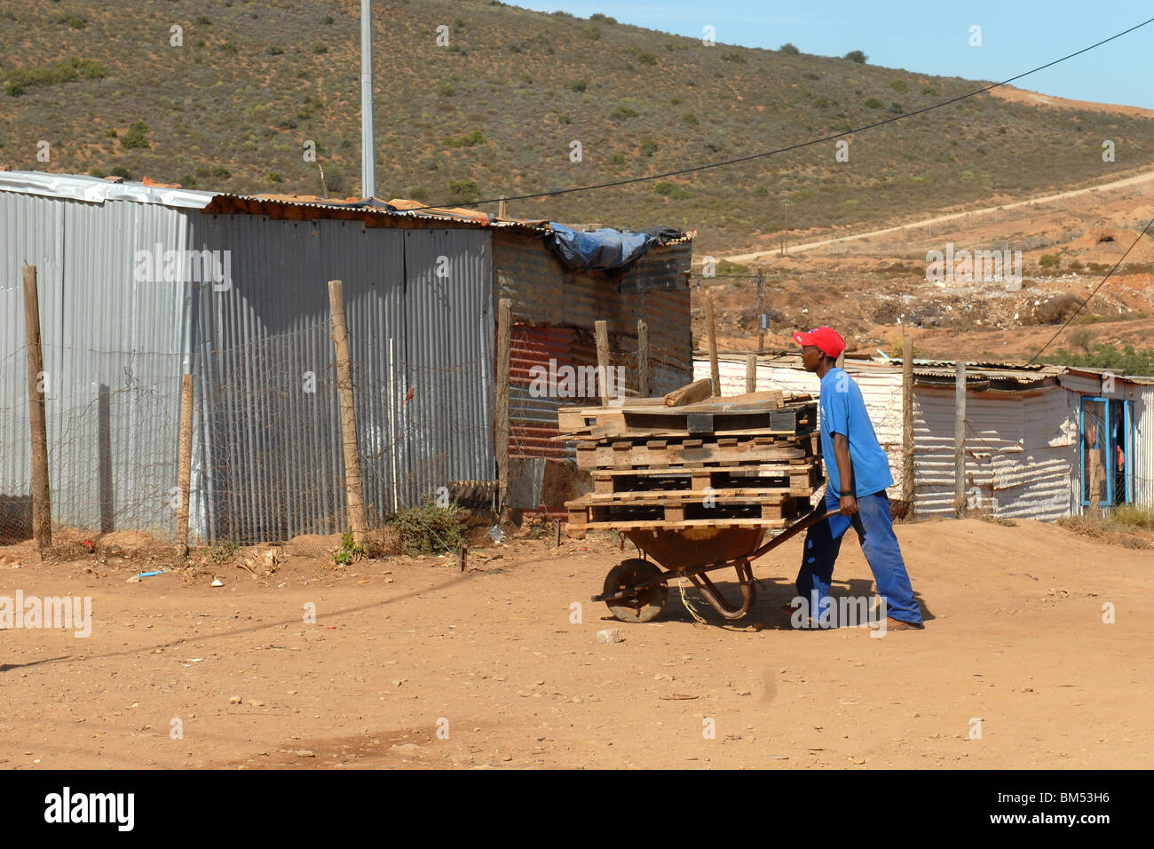 Mann bei der Arbeit mit seiner Schubkarre im township Stockfoto