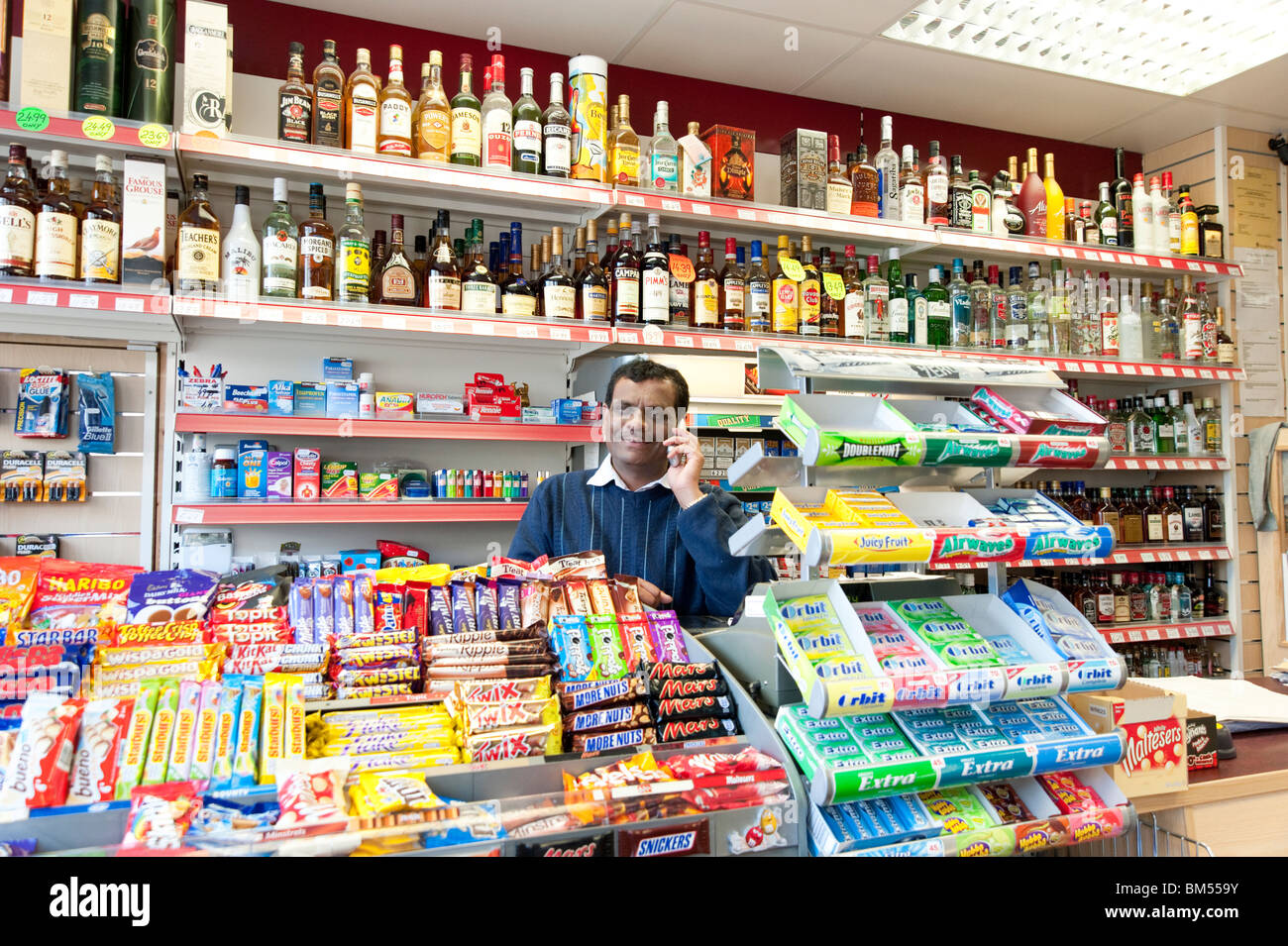Indische Spirituosengeschäft Besitzer in seiner Ecke Shop, London, England, UK Stockfoto